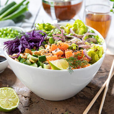 Lachsbowl mit Salat, Rotkohl, Limette, Gurke und Cashewnüssen